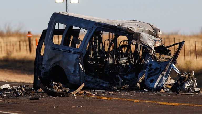 The damaged bus lies on the side of the road at the site of a fatal car crash