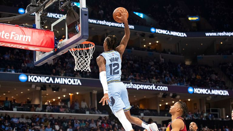 Memphis Grizzlies guard Ja Morant (12) climbs to dunk against the Cleveland Cavaliers during the second half of an NBA basketball game on Wednesday, Oct. 20, 2023, in Memphis, Tenn.  (AP Photo/Nikki Boertman)