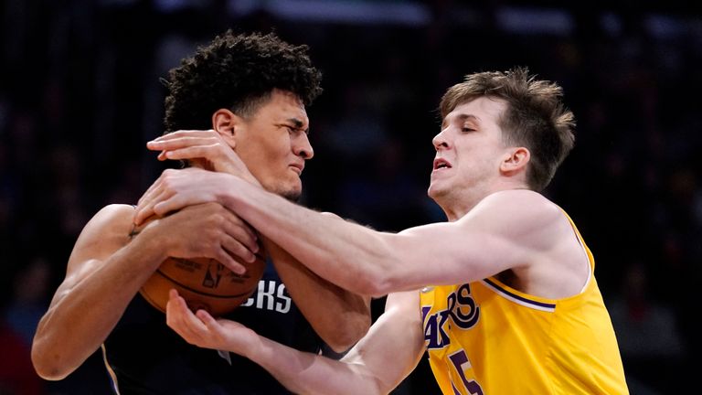 Dallas Mavericks guard Josh Green, left, and Los Angeles Lakers guard Austin Reeves grapple for the ball during the first half of an NBA basketball game