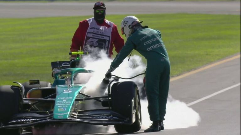 Sebastian Vettel runs to grab an extinguisher while his engine starts smoking.  