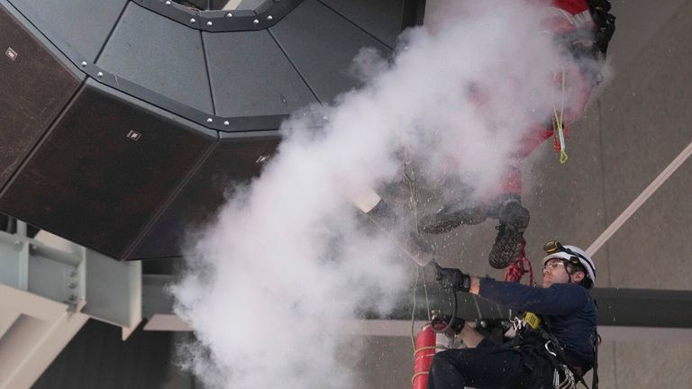 A fire extinguisher is used on a loudspeaker assembly that hangs from the ceiling of the arena after play is suspended and the building is evacuated.